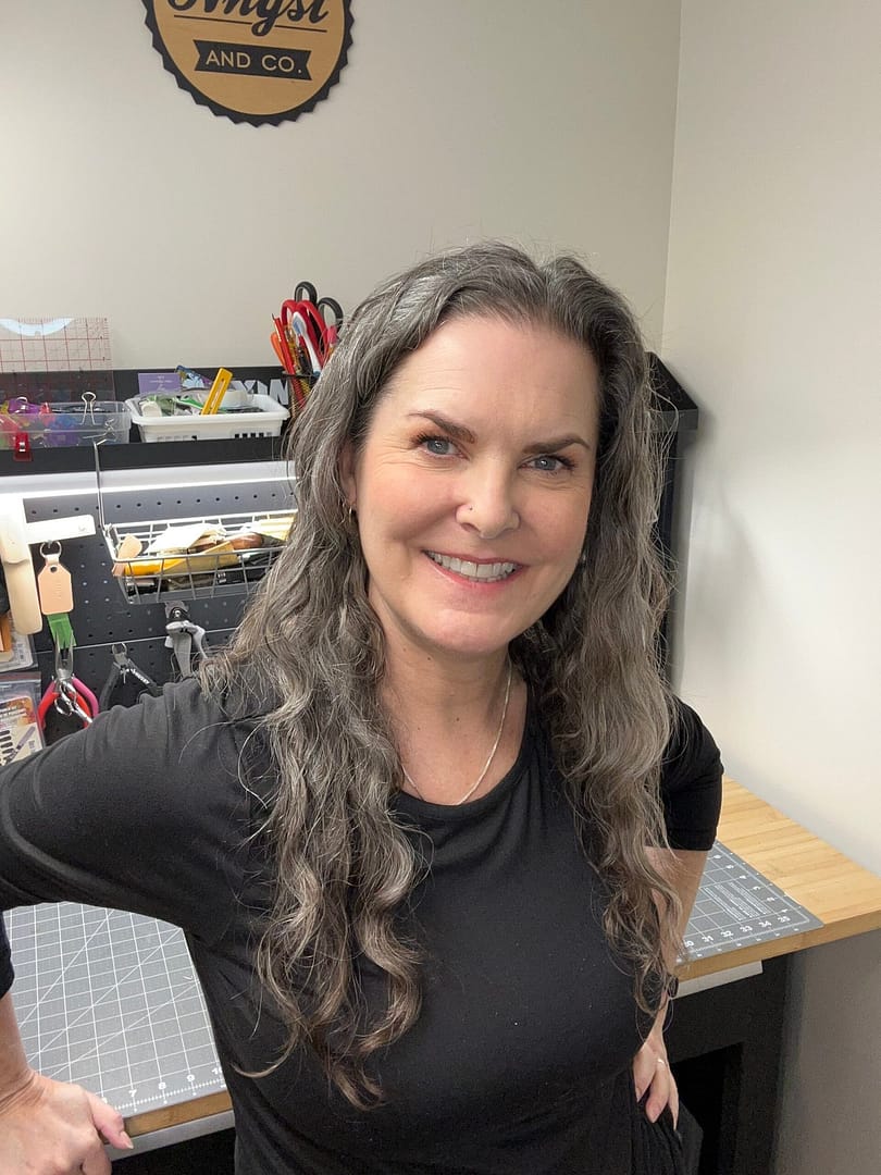 Kim, leather artisan and founder of Angst and Co., smiling in workshop